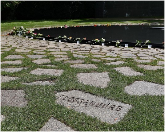 Inmitten der Gedenkstätte findet sich ein Teich, um den einzeln niedergelegte Blumen drapiert sind, viele noch mit einem brennenden Teelicht versehen.
Der gesamte Teich ist mit im Rasen luftig verlegten Natursteinplatten versehen. Manche Steinplatten tragen die Namen der Vernichtungslager, im Bild im Vordergrund 